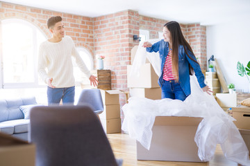 Fototapeta na wymiar Young asian couple having fun playing with bubble wrap smiling happy moving to a new house