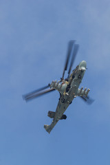 A military camouflage helicopter flying in the blue sky