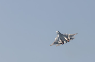 A military fighter jet flying in the gray sky