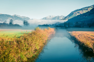 Obraz premium Sunny morning scene near Zell lake. Foggy autumn view of Austrian Alps. Beauty of nature concept background. Instagram filter toned.