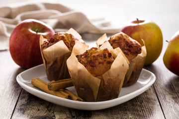 Apples and cinnamon muffins on wooden table.