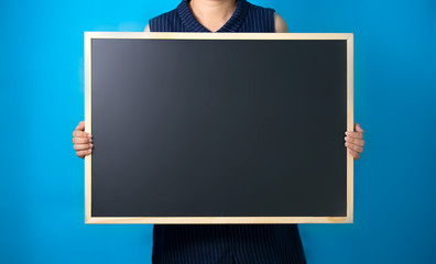 midsection of women holding blackboard against blue background