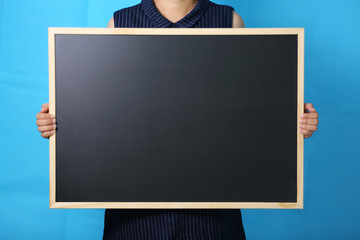 midsection of women holding blackboard against blue background