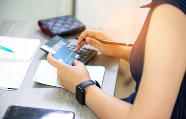 Obraz premium midsection of woman with credit card book bank and calculator paying bills online indoor 