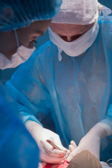 Children's surgeons perform urological surgery. A man and a woman in a mask, and a blue sterile gown, in the operating room.