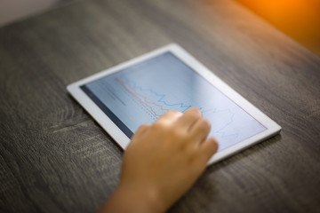 Closeup shot of an unrecognisable businesswoman analysing graphs on a digital tablet in an office