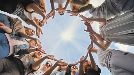 A large group of students makes a circle out of their hands.