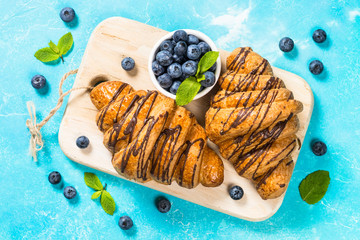 Croissant with fresh berries on blue.