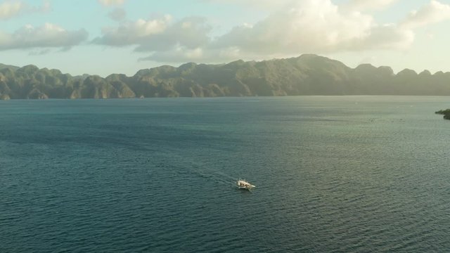 Aerial view seascape bay with islands and mountains sunset. tour boat in sea. traditional Filipino wooden outrigger boat called a banca . Motorboat crossing ocean. Banca boat in the Philippines