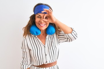 Fototapeta premium Middle age tourist woman wearing neckpillow and sleep mask over isolated white background doing ok gesture with hand smiling, eye looking through fingers with happy face.