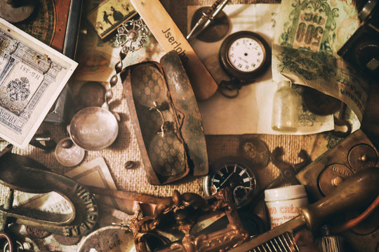 Different antique items on the table: old pocket watches, banknotes and coins of the Russian Empire, glasses in a case, silverware. Vintage background from a collection of antiques. Selected focus