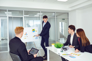 A group of young businessmen are listening to a coach's speech at office.