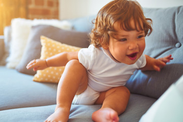 Beautiful toddler child girl wearing white t-shirt sitting on the sofa