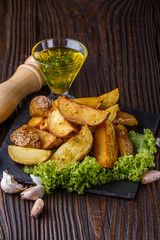 Potato wedges baked in their skins with lettuce on wooden background.