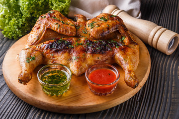 Roasted chiken on wooden board with sauce