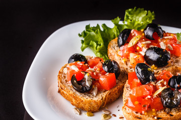 Italian bruschetta with tomato, black olives, lettuce and mustard