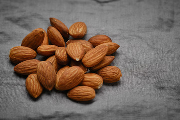 almonds isolated on grey linen background, close up. macro shot