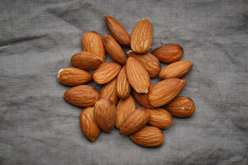 almonds isolated on grey linen background, close up. macro shot