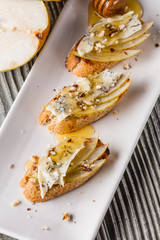 Appetizer bruschetta with pear, honey, walnut and blue cheese on white plate