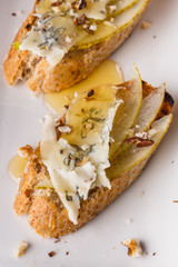 Appetizer bruschetta with pear, honey, walnut and blue cheese on white plate