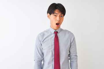 Chinese businessman wearing elegant tie standing over isolated white background In shock face, looking skeptical and sarcastic, surprised with open mouth