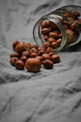 hazelnuts sprinkled from a glass jar on linen. heap or stack of hazelnuts.