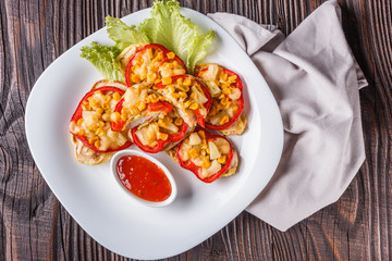 Chicken fillet in a batter with corn, paprika, lettuce and spicy tomato sauce on white plate