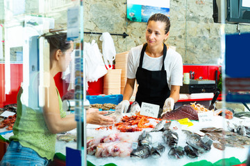 Glad seller offering seafood to female