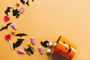 Halloween candy flat lay. Halloween candy, skulls, black bats and ghost paper decorations scattered...