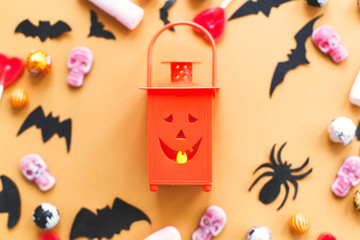 Halloween flat lay, jack o lantern and candy, skulls, black bats and ghost paper decorations on yellow background.Trick or treat concept. Happy Halloween