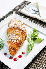 fresh croissant and cappuccino on table