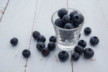 blueberries in glass shot on white wooden  background, fruit flavor concept