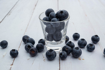 blueberries in glass shot on white wooden  background, fruit flavor concept