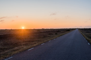 Sunrise by a straight country road in a great plain grassland