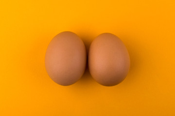 Brown chicken eggs lie on an orange background
