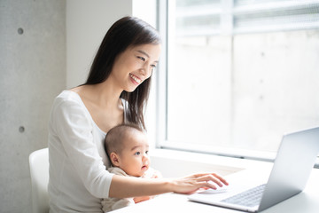 Young woman using laptop computer with her baby