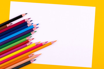 Colored sharpened wooden pencils lie on a white sheet of paper for creativity, drawing, notes, texts and letters