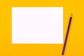 A white sheet of paper for drawings, texts and notes next to a purple pencil lies on an orange background