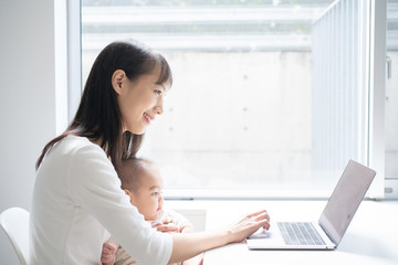 Young woman using laptop computer with her baby