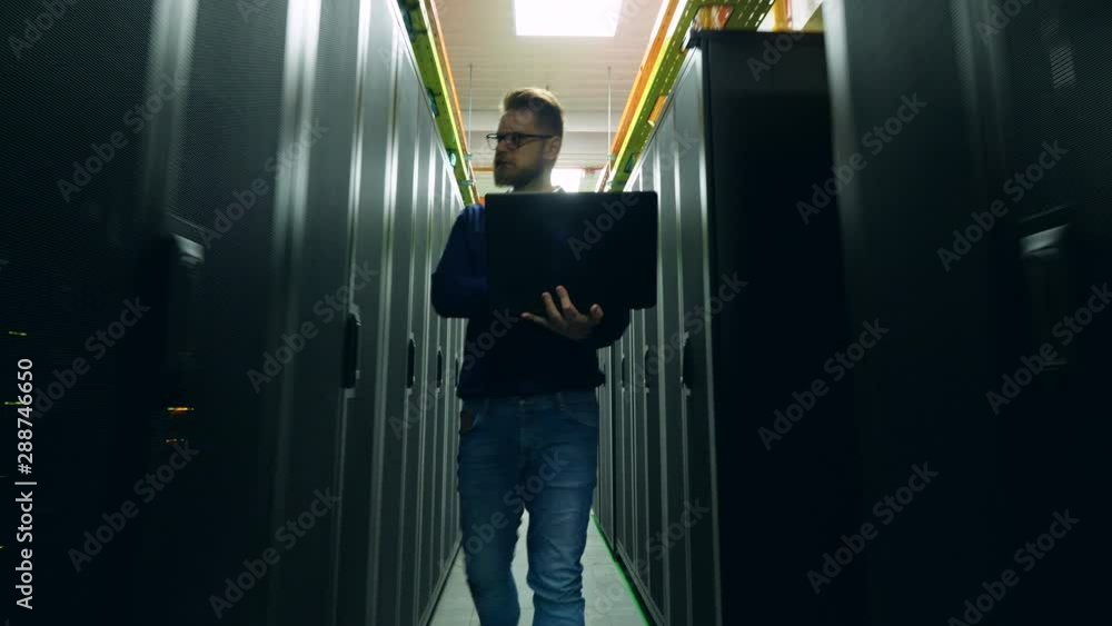 Poster computer engineer is walking along the datacenter