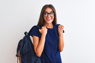 Young beautiful student woman wearing backpack and glasses over isolated white background screaming proud and celebrating victory and success very excited, cheering emotion