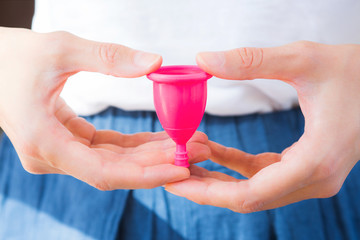 Woman holding a pink menstrual cup in hands. Closeup