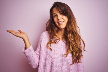Young beautiful woman wearing sweater standing over pink isolated background smiling cheerful...