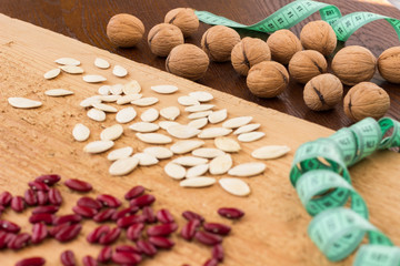 Beans and pumpkin seeds, a glass of water and walnuts, a measuring tape. Low calorie diet concept