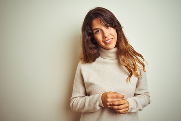 Obraz premium Young beautiful woman wearing winter sweater standing over white isolated background with hands together and crossed fingers smiling relaxed and cheerful. Success and optimistic