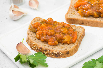Bread with vegetable caviar on a white tray on a light gray background