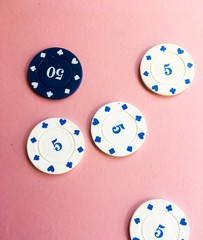 Blue and white casino chips on pink background. Poker play.