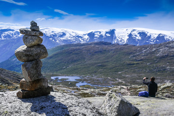 Stone cairn on the way to Trolltung among a mountain landscape with a traveler in Norway