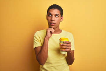 Young handsome arab man drinking take away coffee over isolated yellow background serious face thinking about question, very confused idea