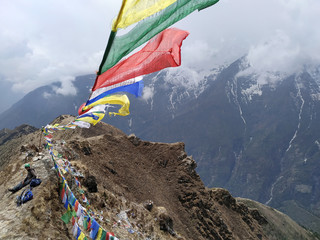 Colorful buddhist prayer flags waving in the Himalayas against a cloudy sky. Nature, religion, healthy lifestyle, outdoors, east asian culture, hiking, travel and tourism concept.